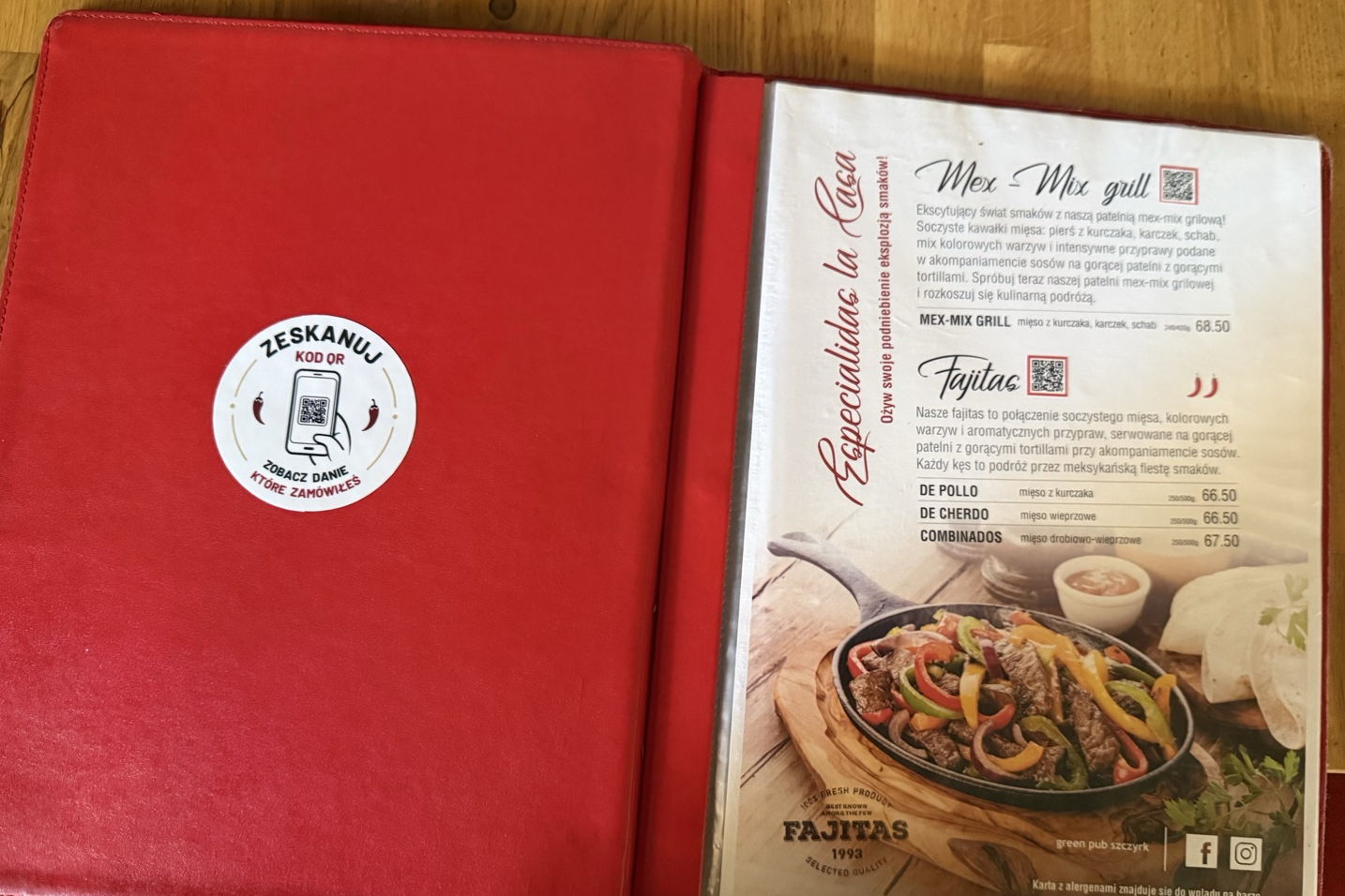 Otwarta karta dań Green Pub Sjesta na stole, na okładce okrągła naklejka z kodem QR i napisem Zeskanuj kod QR, zobacz danie które zamówiłeś